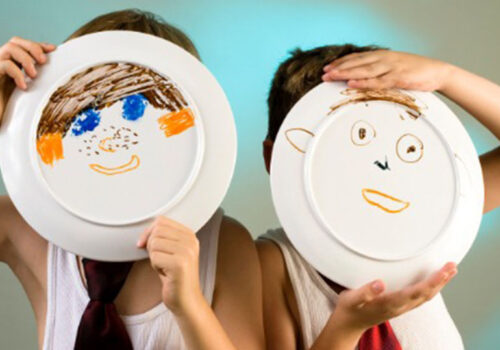 Young boys in undershirt and ties with a faces painted on a plates.