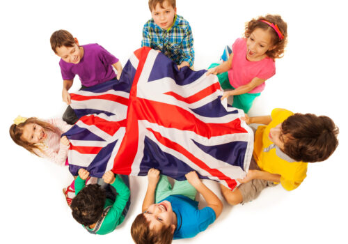 Top view of seven kids holding English flag in the middle of their circle, isolated on white background