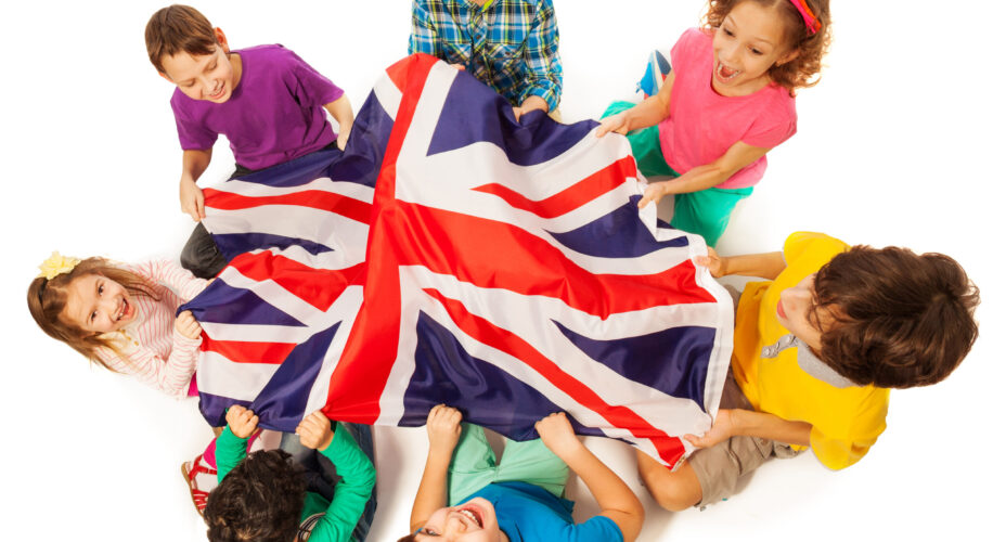 Top view of seven kids holding English flag in the middle of their circle, isolated on white background